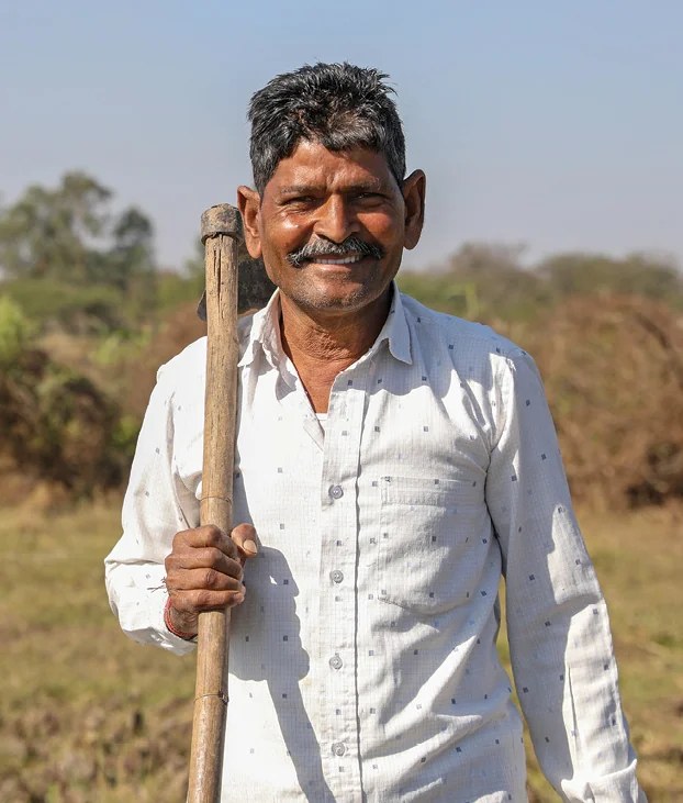 Balailal Maity standing with a staff in a field near Rabindranagar village