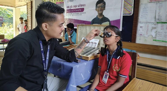 An Adani Foundation optometrist screening a schoolgirl&rsquo;s vision with a trial frame at an eye-care camp