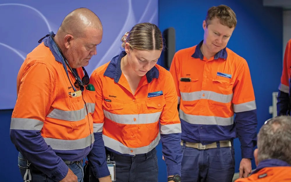 Frontline team members in high-visibility safety gear reviewing operations