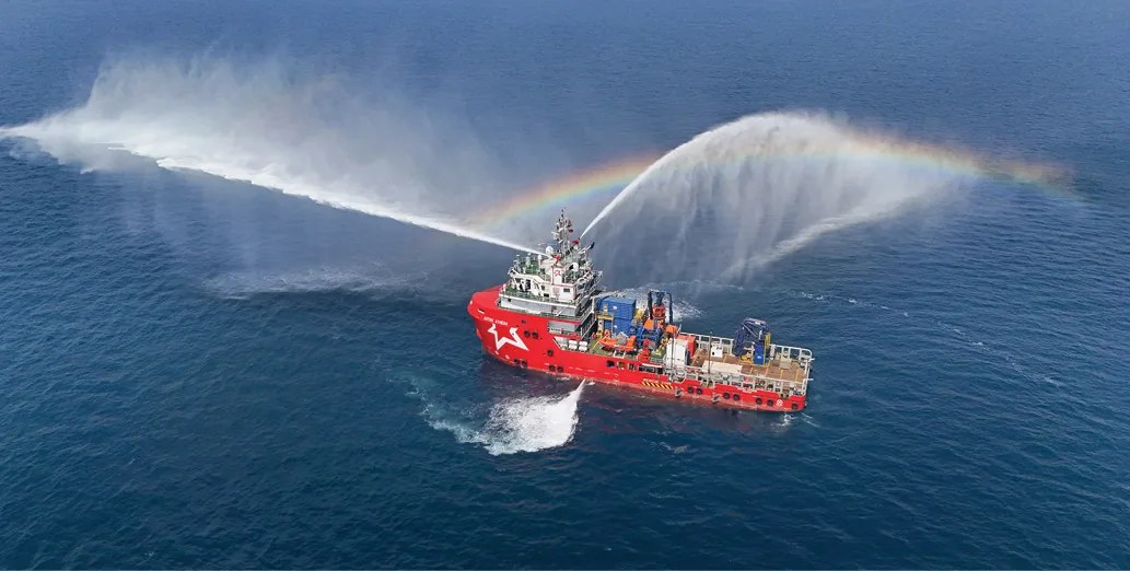An APSEZ offshore support vessel performing a fire-fighting water demonstration at sea